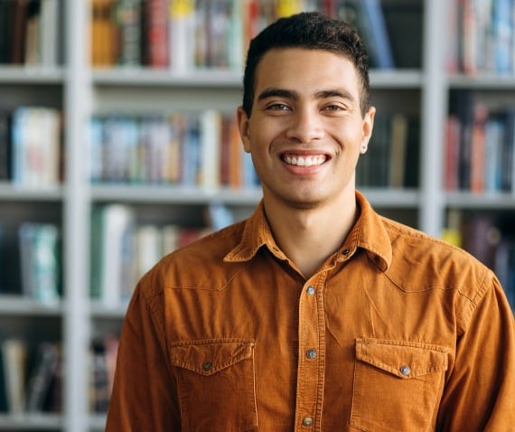 man standing in front bookshelf