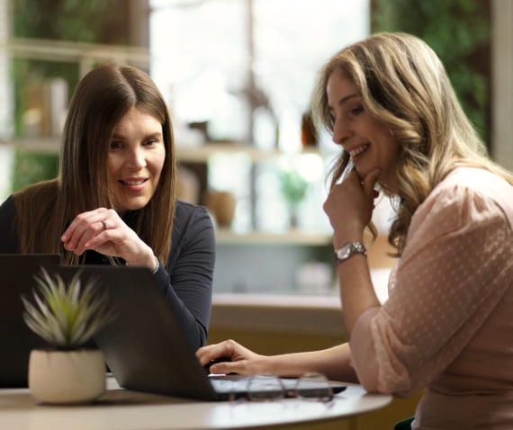 two women working together over laptop