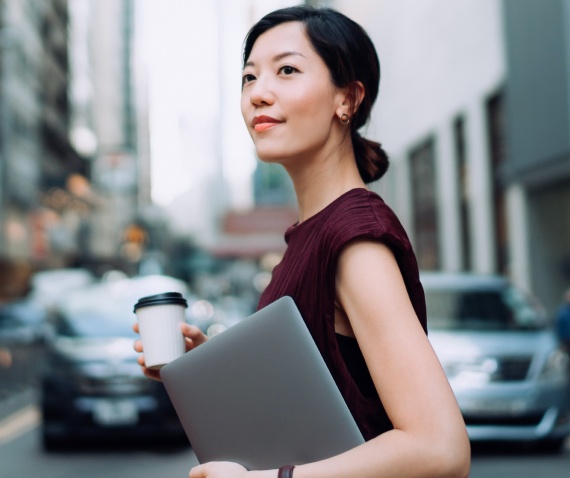 woman with laptop crossing street