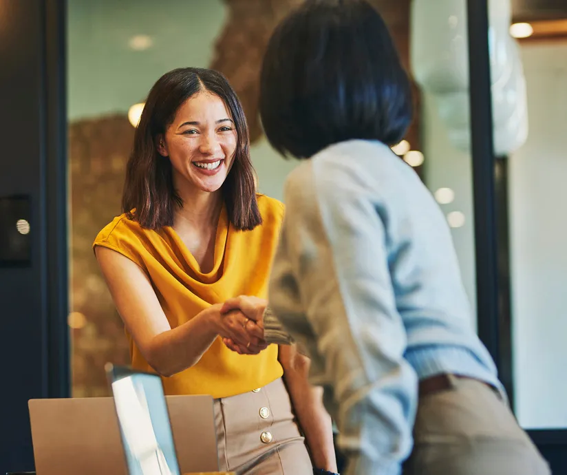 Two women smiling and shaking hands