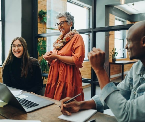 A group gathered around a desk and smiling and laughing together