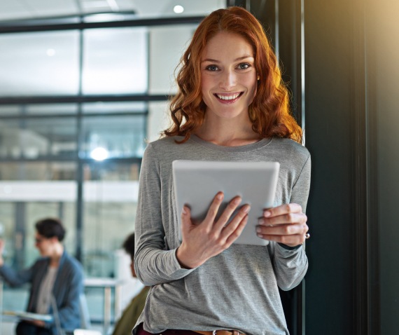 A woman holding a tablet and smiling at the camera