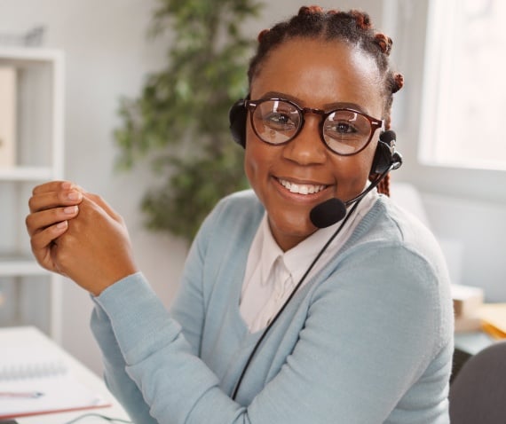 A woman wearing a headset with a mic smiling at the camera